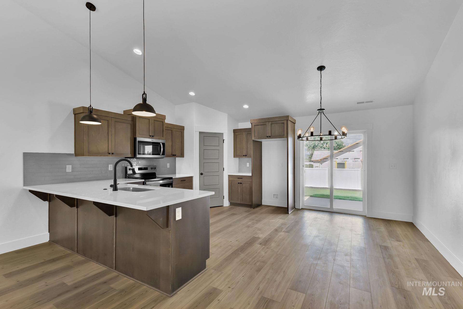 1160 Velvet Loop Wilder, ID 83676 - Photo 5 of 29 Kitchen with hanging light fixtures, a breakfast bar area, a peninsula, lofted ceiling, and stainless steel appliances