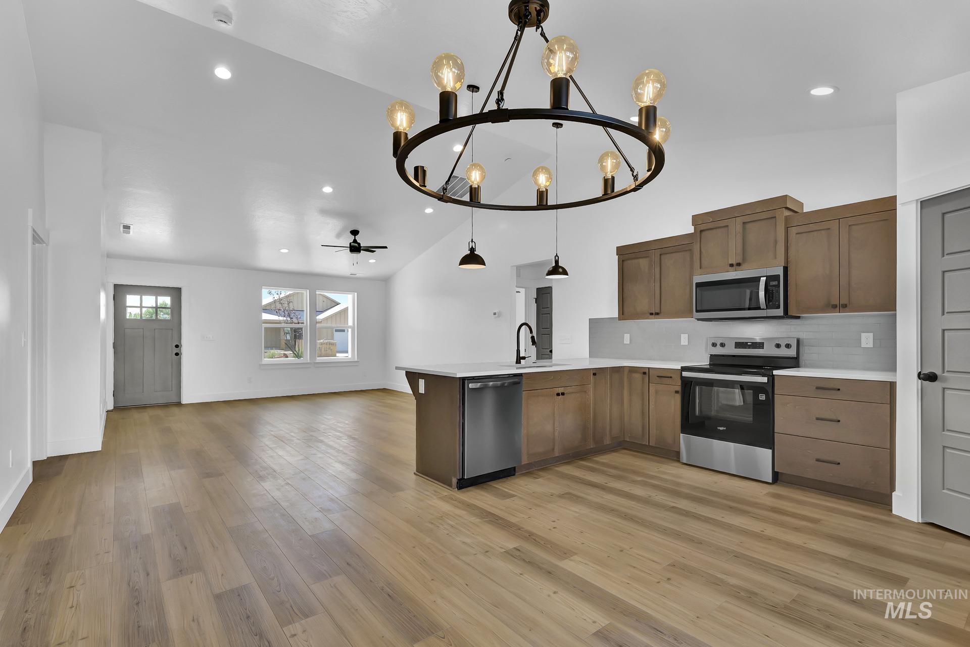 1160 Velvet Loop Wilder, ID 83676 - Photo 29 of 29 Kitchen featuring a chandelier, stainless steel appliances, open floor plan, backsplash, and ceiling fan