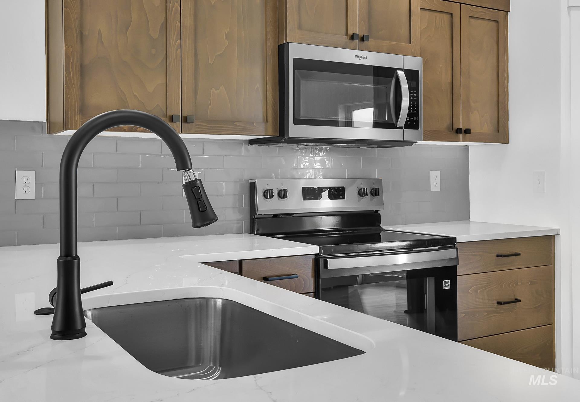 1160 Velvet Loop Wilder, ID 83676 - Photo 8 of 29 Kitchen featuring appliances with stainless steel finishes, brown cabinetry, decorative backsplash, and light stone counters