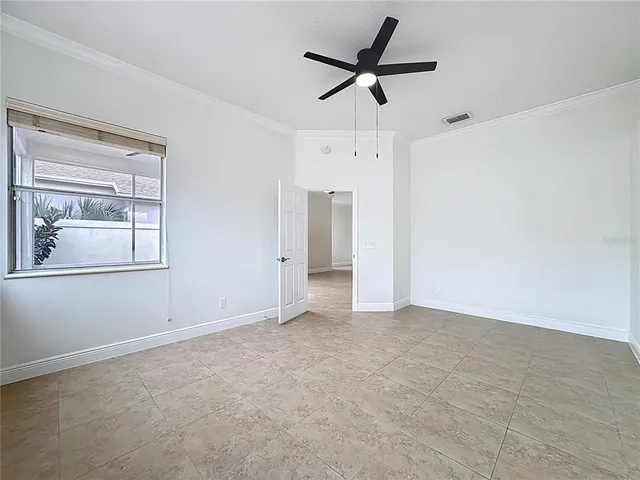 a view of an empty room and chandelier fan