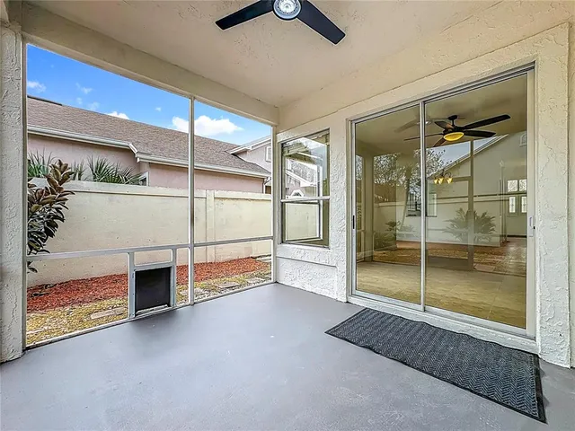 a view of an empty room with windows and ceiling fan