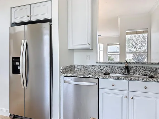 a kitchen with granite countertop a sink a window and cabinets