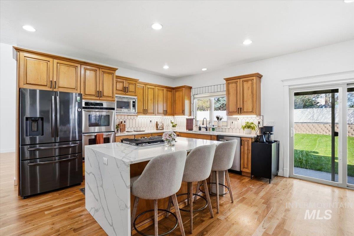 342 North Clearpoint Way Eagle, ID 83616 - Photo 11 of 50 Kitchen featuring stainless steel appliances, wood finish cabinets, a center island, a breakfast bar, and recessed lighting
