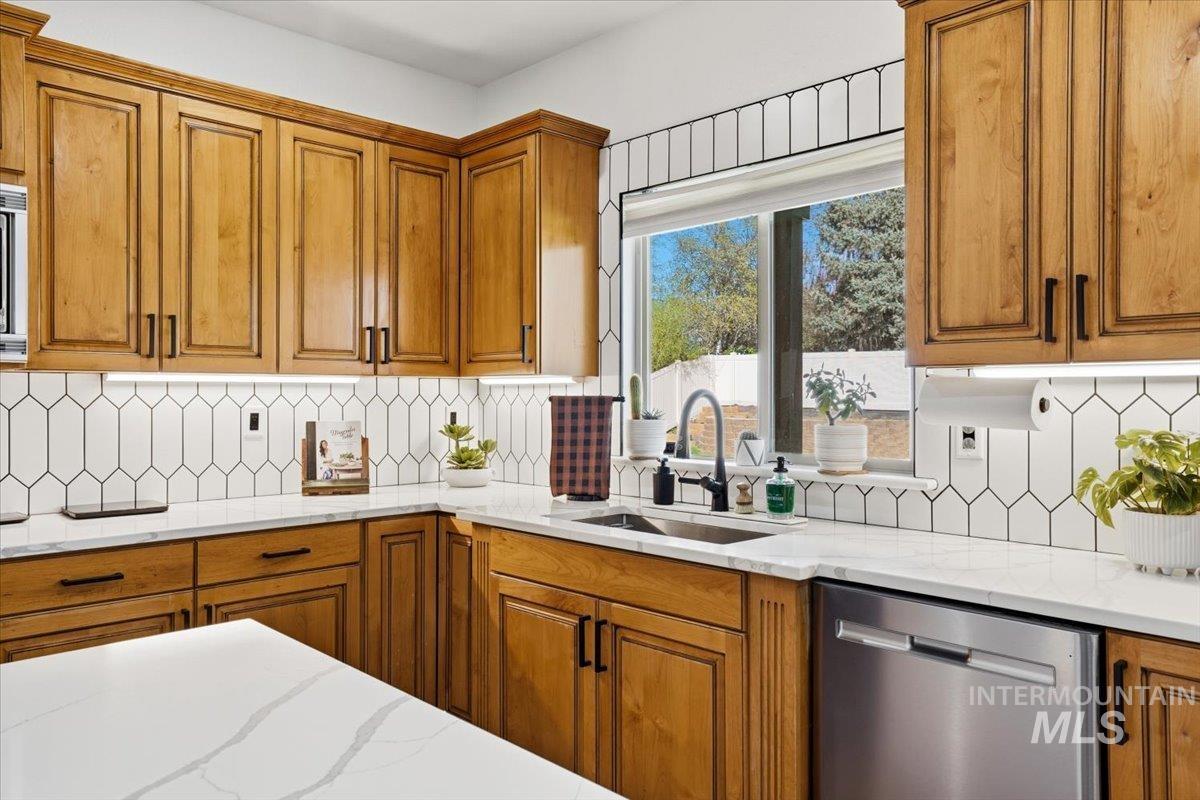 342 North Clearpoint Way Eagle, ID 83616 - Photo 14 of 50 Kitchen with wood finish cabinetry, light stone counters, dishwasher, and tasteful backsplash