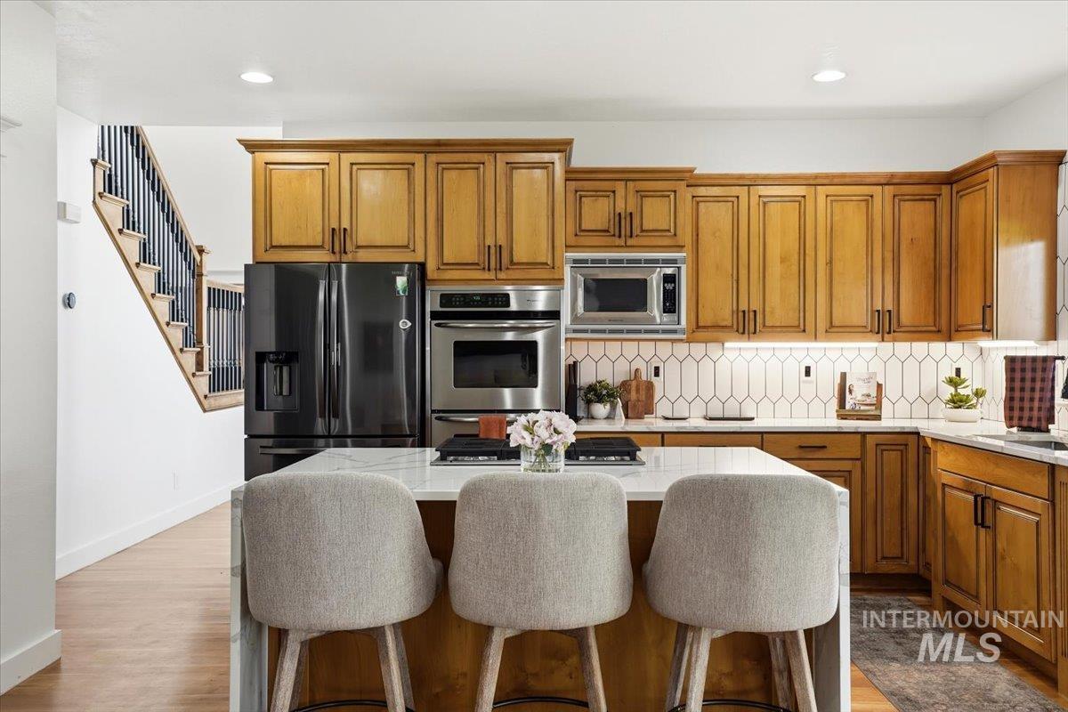 342 North Clearpoint Way Eagle, ID 83616 - Photo 15 of 50 Kitchen featuring wood finish cabinets, stainless steel appliances, light stone countertops, tasteful backsplash, and a kitchen island