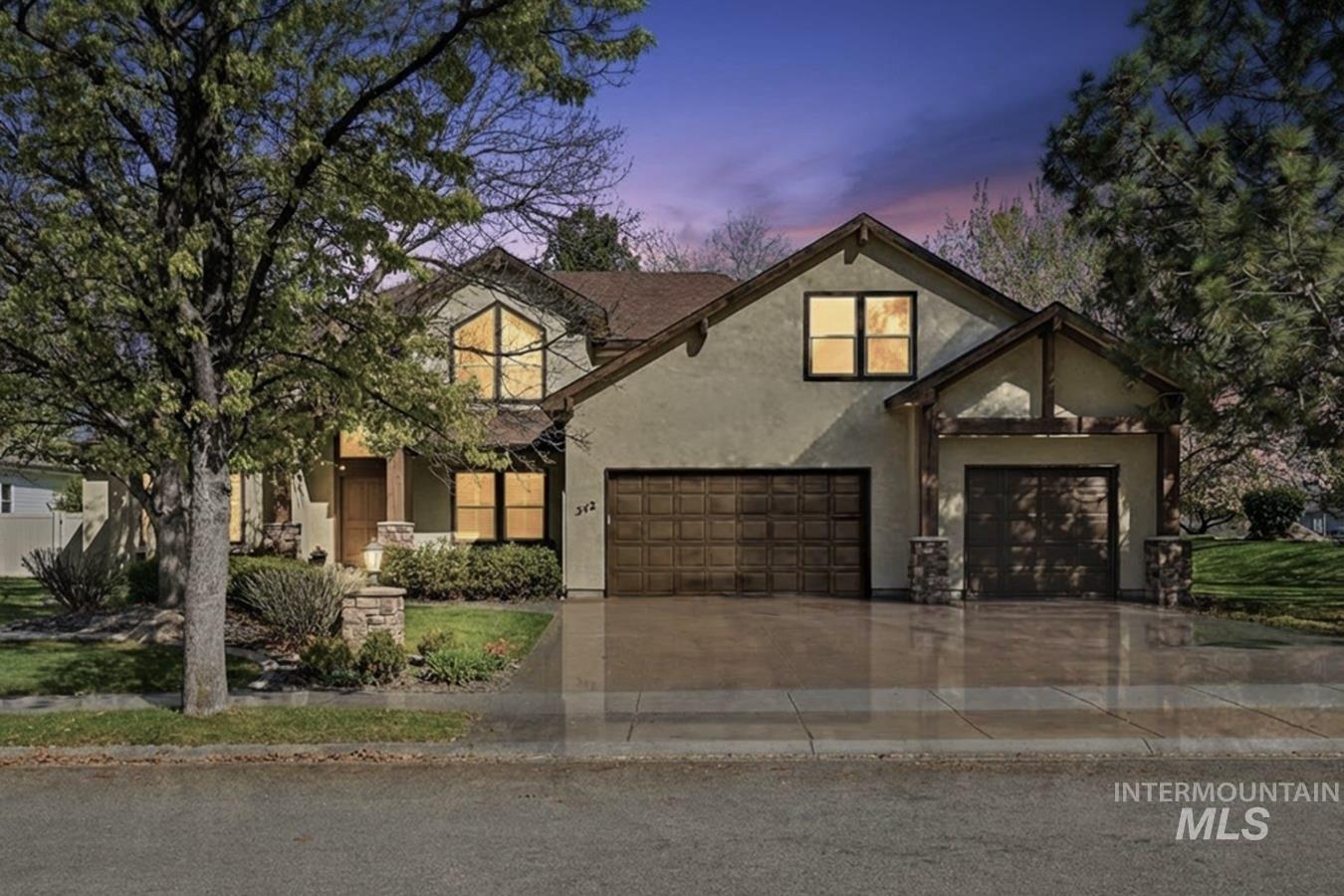 342 North Clearpoint Way Eagle, ID 83616 - Photo 38 of 50 Stucco exterior with a peaked roofline, featuring two attached garages with paneled doors, exposed beam detailing, and stone-clad columns