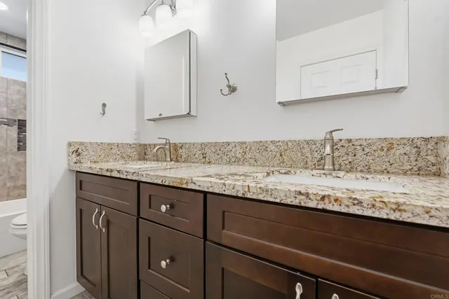a sink with granite countertop cabinets and window