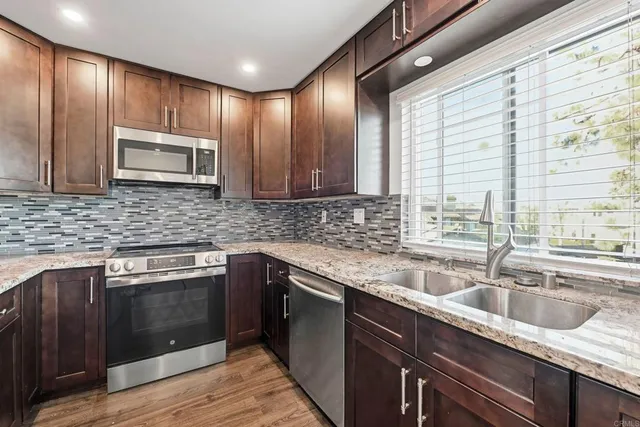 a kitchen with stainless steel appliances granite countertop wooden cabinets a sink and dishwasher next to a window