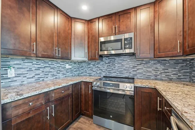 a kitchen with granite countertop wooden cabinets stainless steel appliances and a counter top