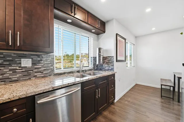 a kitchen with granite countertop a sink and a white wooden cabinets