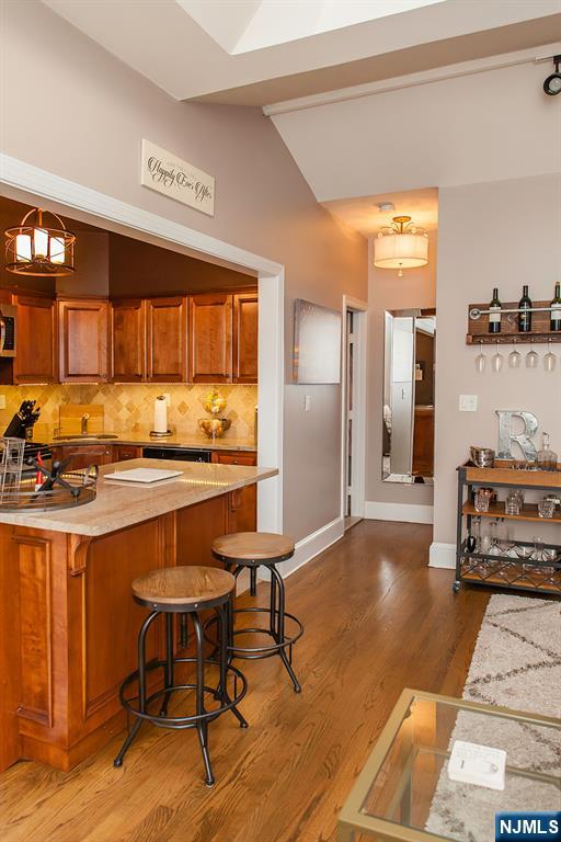 309 1st Street, Unit 3C Hoboken, NJ 07030 - Photo 5 of 13 a kitchen with stainless steel appliances kitchen island granite countertop a table chairs in it and wooden floors