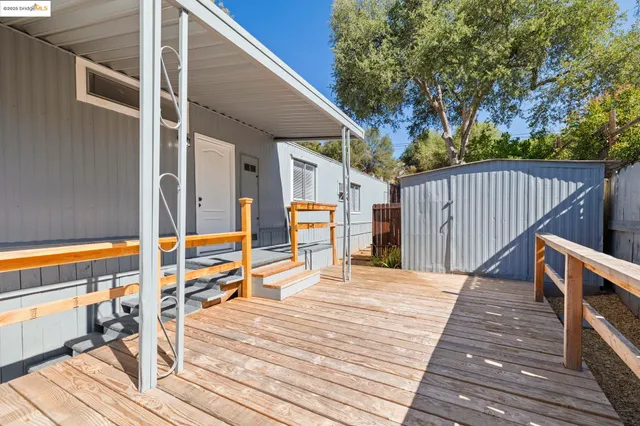 a backyard of a house with plants and trees with wooden fence