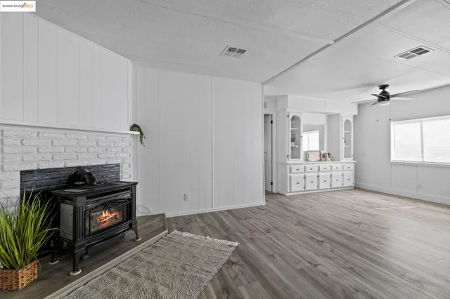 a view of an empty room with wooden floor and a fireplace