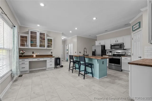 a large white kitchen with stainless steel appliances granite countertop a stove and a sink