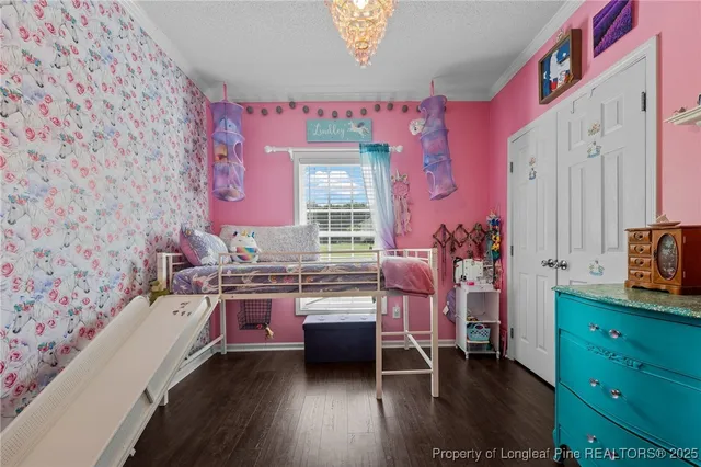 a view of a bedroom with a bed and wooden floor
