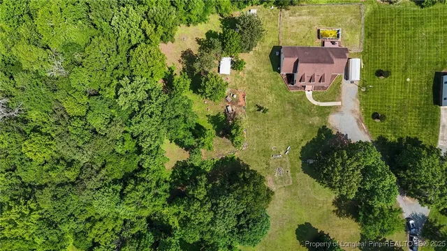 an aerial view of residential house with outdoor space and trees all around