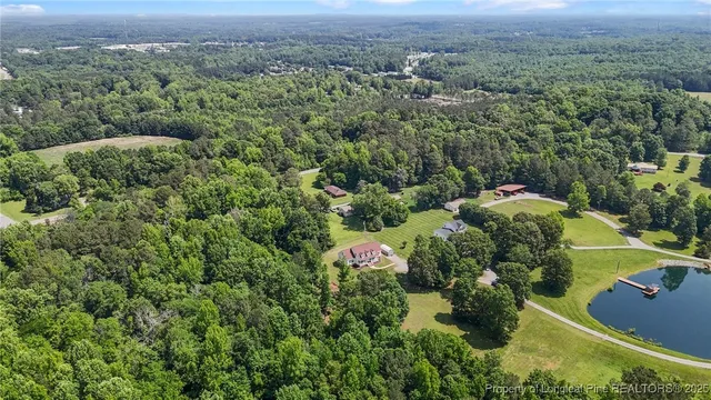an aerial view of residential house with outdoor space and trees all around