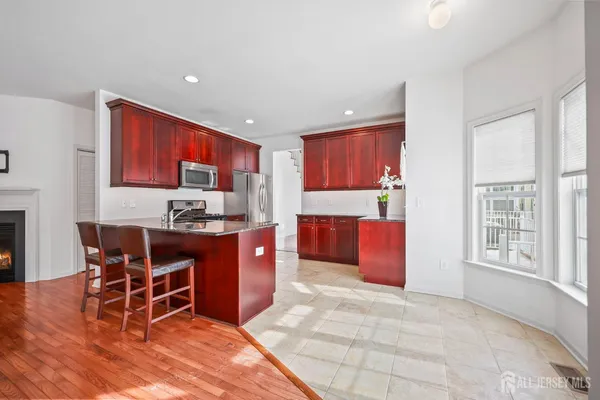 a kitchen with stainless steel appliances kitchen island granite countertop a table chairs in it and a window