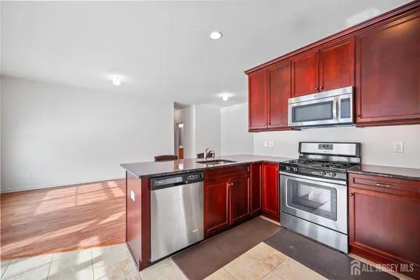 a kitchen with stainless steel appliances granite countertop a stove a sink and a microwave