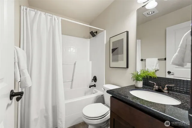 a bathroom with a granite countertop sink toilet a mirror a shower and a tub