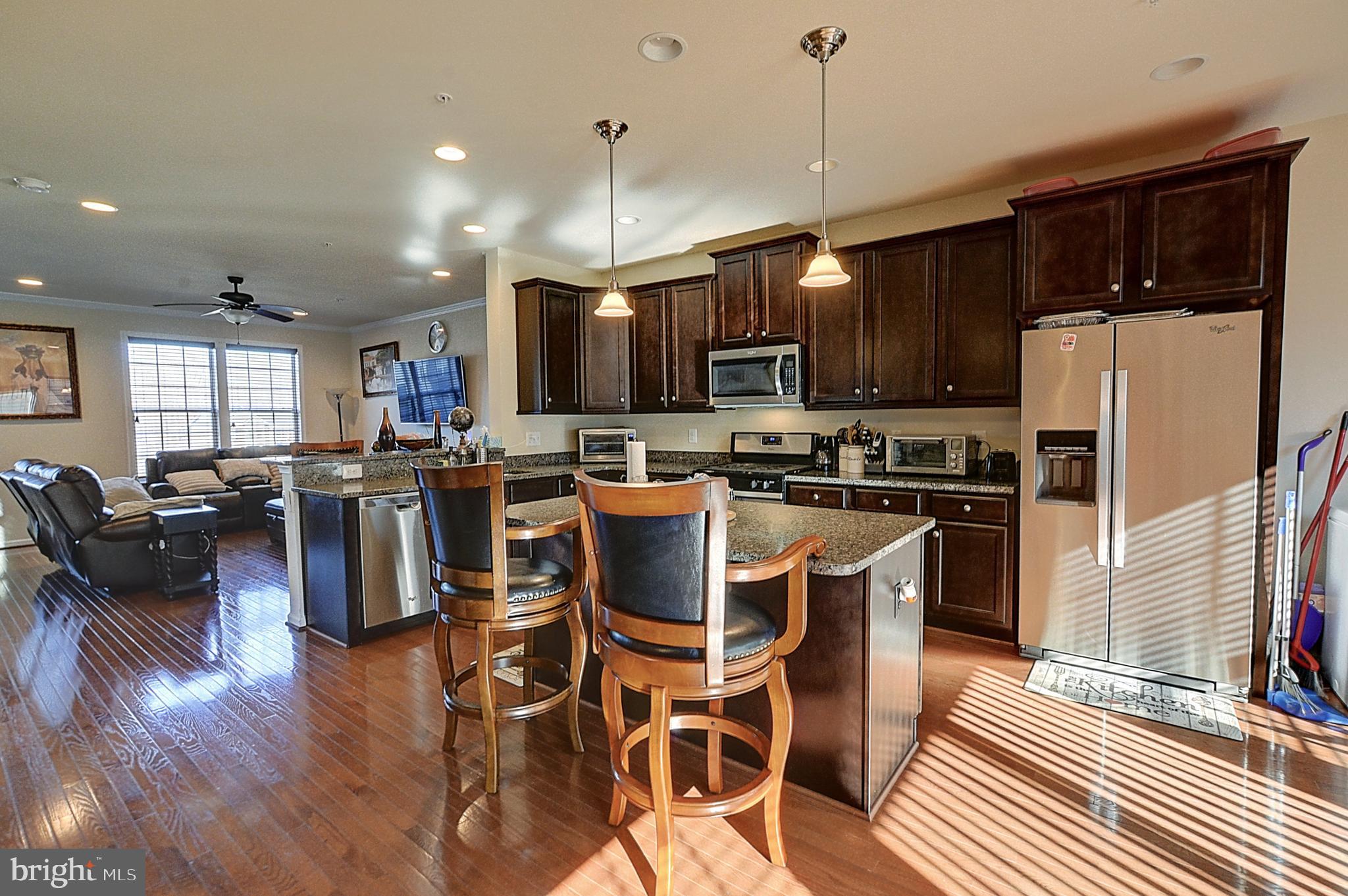 12801 Ricker Road Upper Marlboro, MD 20772 - Photo 8 of 27 a kitchen with stainless steel appliances granite countertop a refrigerator a stove top oven a sink dishwasher a dining table and chairs with wooden floor