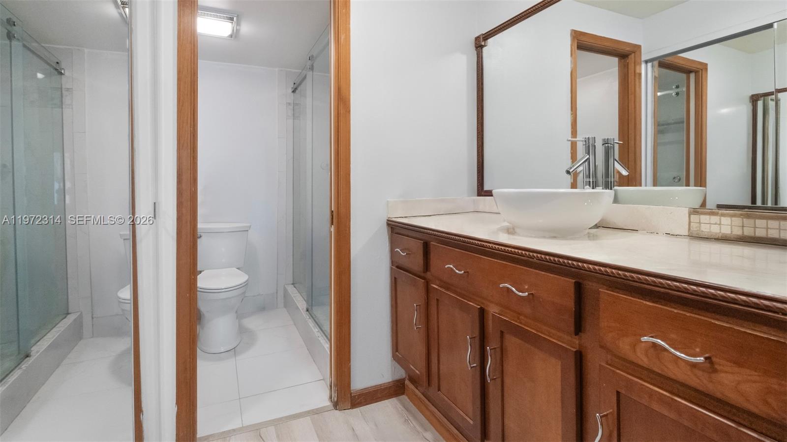 8605 West Sample Road, Unit 202 Coral Springs, FL 33065 - Photo 12 of 26 a bathroom with a granite countertop sink a toilet and a mirror