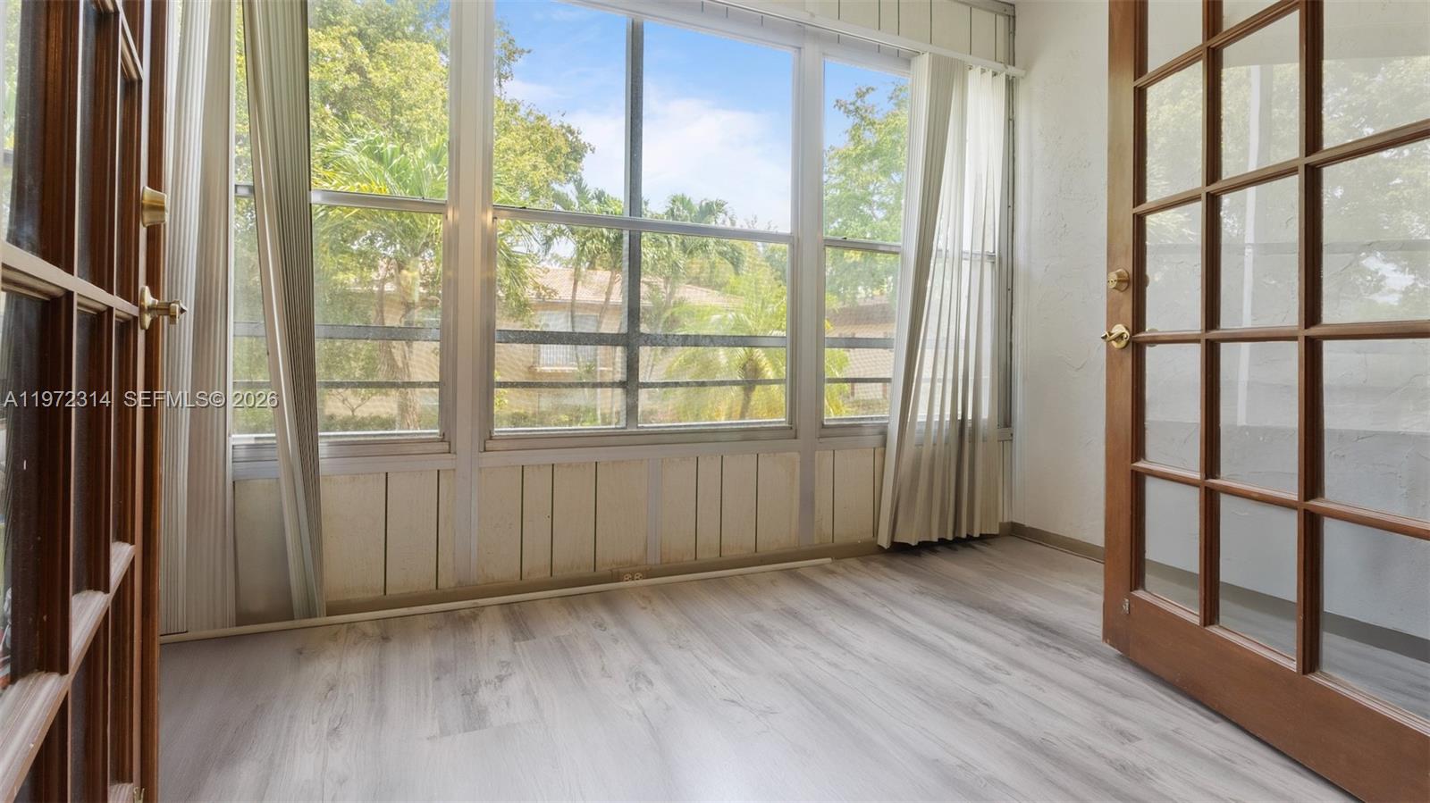 8605 West Sample Road, Unit 202 Coral Springs, FL 33065 - Photo 7 of 26 a view of an empty room with wooden floor and a window