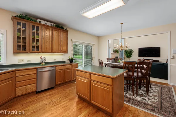 a kitchen with stainless steel appliances granite countertop a stove top oven a sink dishwasher a dining table and chairs with wooden floor