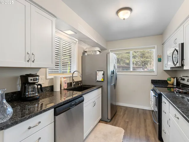 a kitchen with granite countertop a sink a stove and cabinets