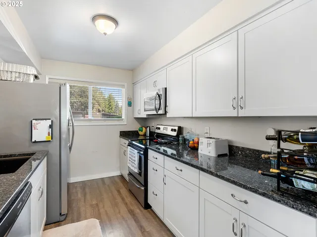 a kitchen with granite countertop white cabinets and white appliances