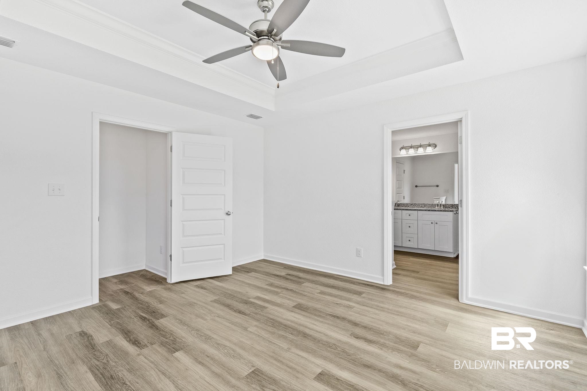 16014 Alabama Avenue Silverhill, AL 36576 - Photo 21 of 50 Unfurnished bedroom with a raised ceiling, ensuite bath, light hardwood / wood-style flooring, and ceiling fan