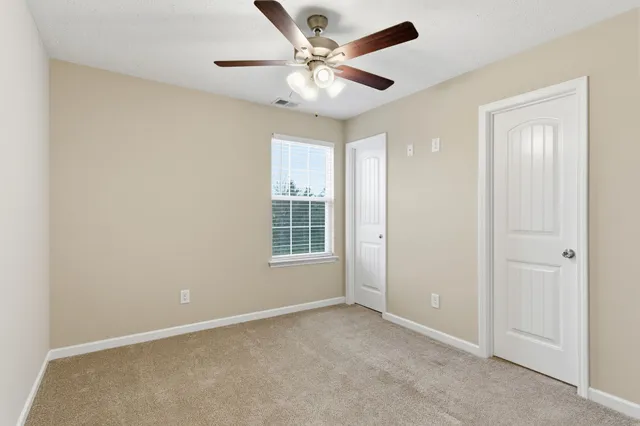 an empty room with windows and ceiling fan
