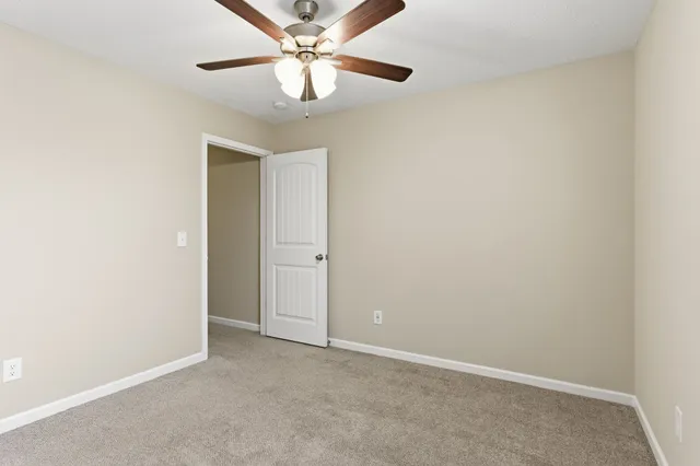 an empty room with a chandelier fan and windows