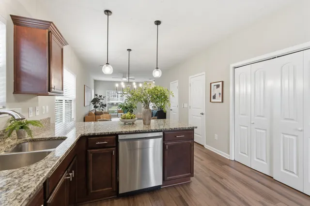 a kitchen with stainless steel appliances granite countertop a sink a stove and a wooden floors