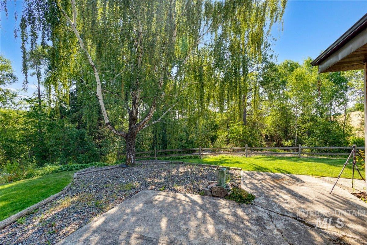 1071 Reynolds Road Princeton, ID 83857 - Photo 42 of 43 Expansive backyard featuring a mature weeping birch tree, concrete patio, gravel landscaping, manicured lawn, and a wooden split-rail fence