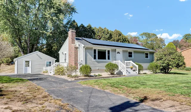 a view of a yard in front of a house with large windows