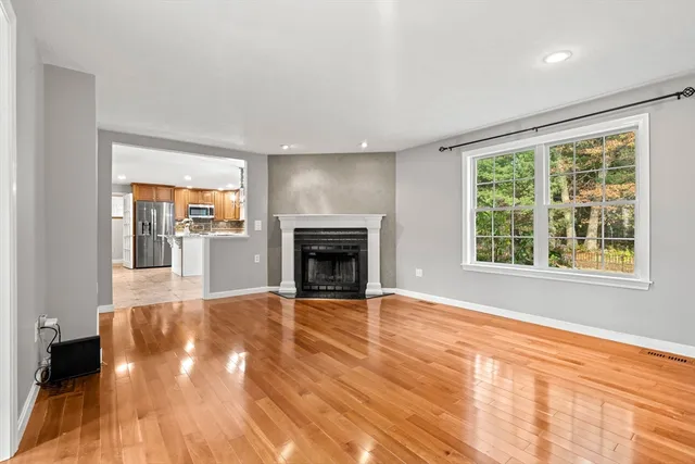a view of empty room with wooden floor and fireplace