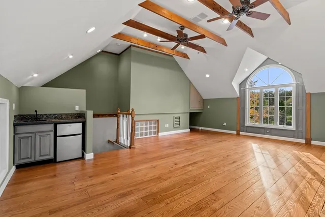 a view of an empty room with wooden floor and a fireplace