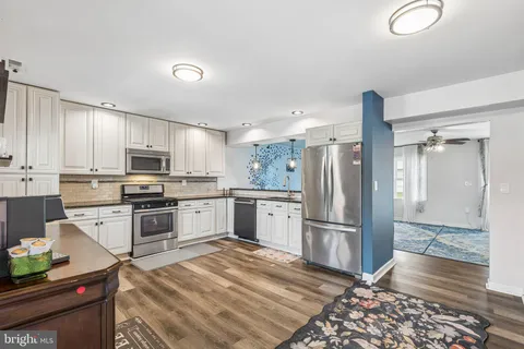 a kitchen with granite countertop a refrigerator stove and wooden floor
