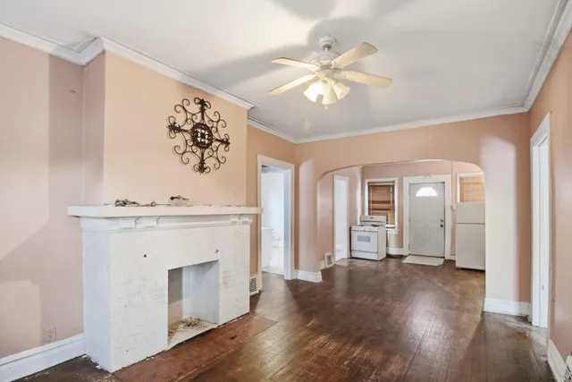 a view of an empty room with wooden floor and a fireplace