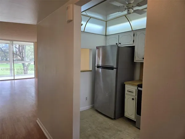 a view of a refrigerator in kitchen and an empty room