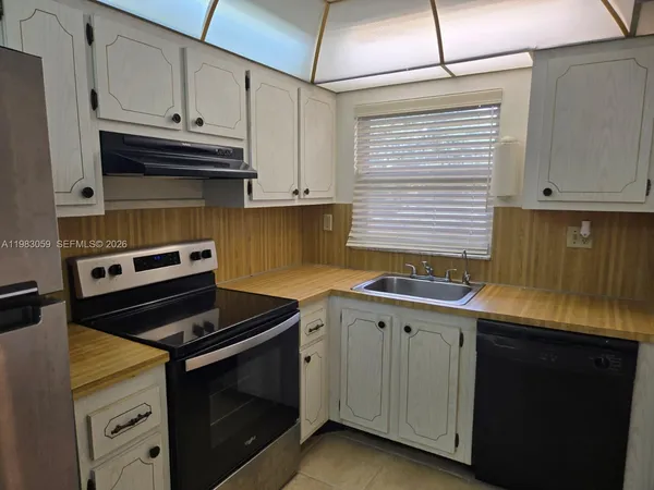 a kitchen with granite countertop a refrigerator stove and white cabinets