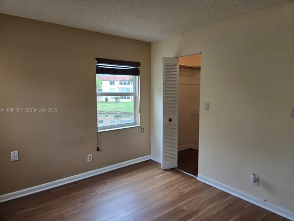 a view of an empty room with closet and wooden floor