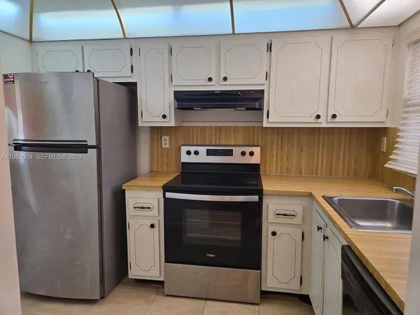 a kitchen with a stove and a refrigerator with white cabinets