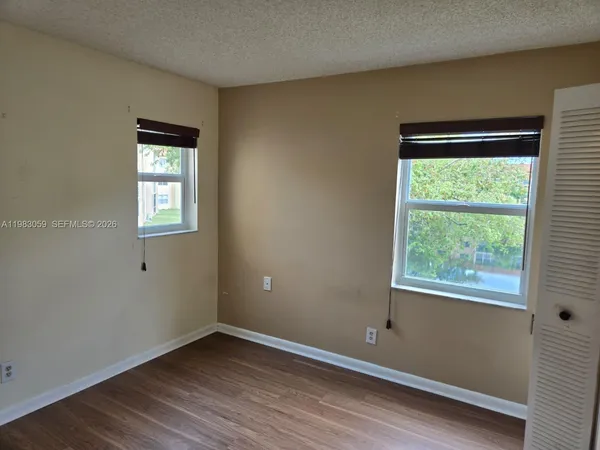 an empty room with wooden floor and windows
