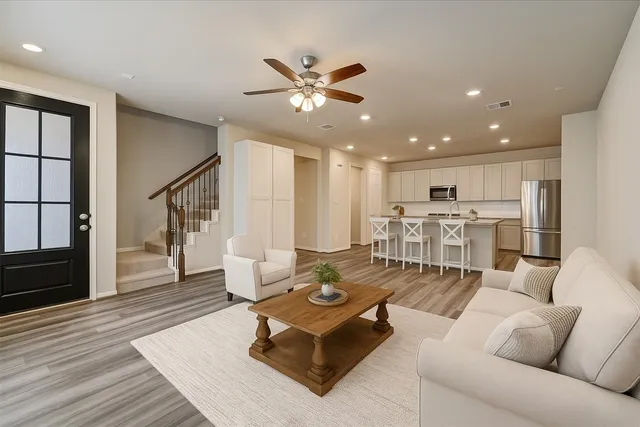 a living room with furniture kitchen view and a wooden floor