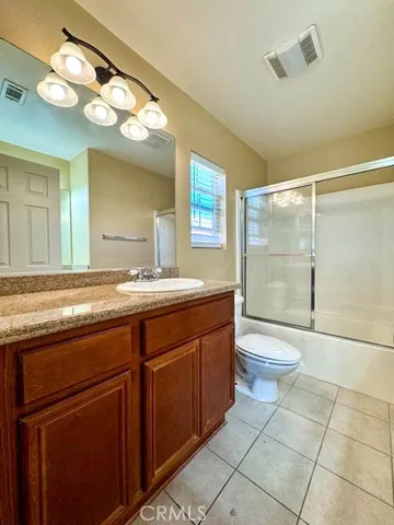 a bathroom with a granite countertop sink a toilet and a mirror