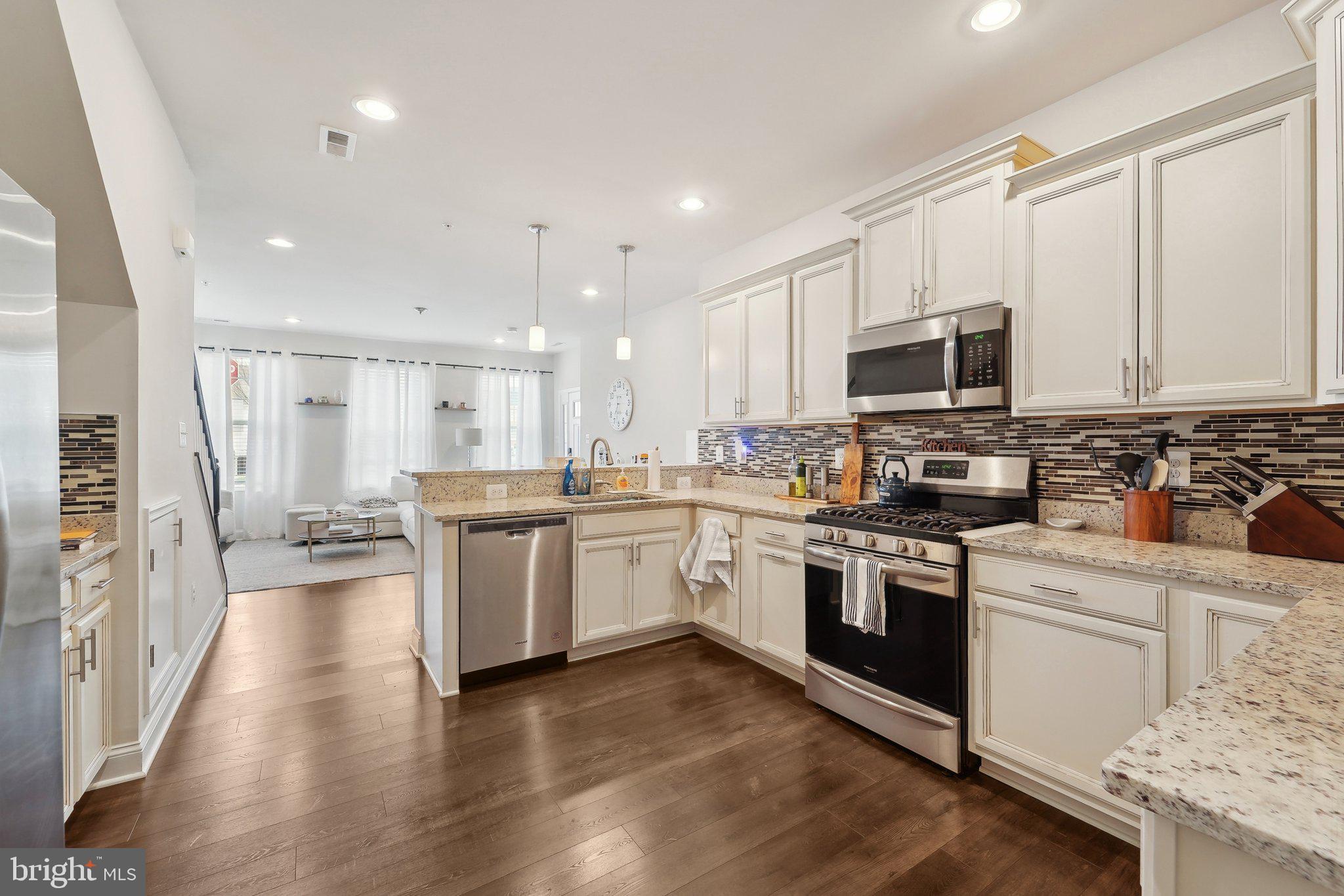 7101 Macon Street Frederick, MD 21703 - Photo 11 of 38 a kitchen with granite countertop appliances cabinets and a wooden floor