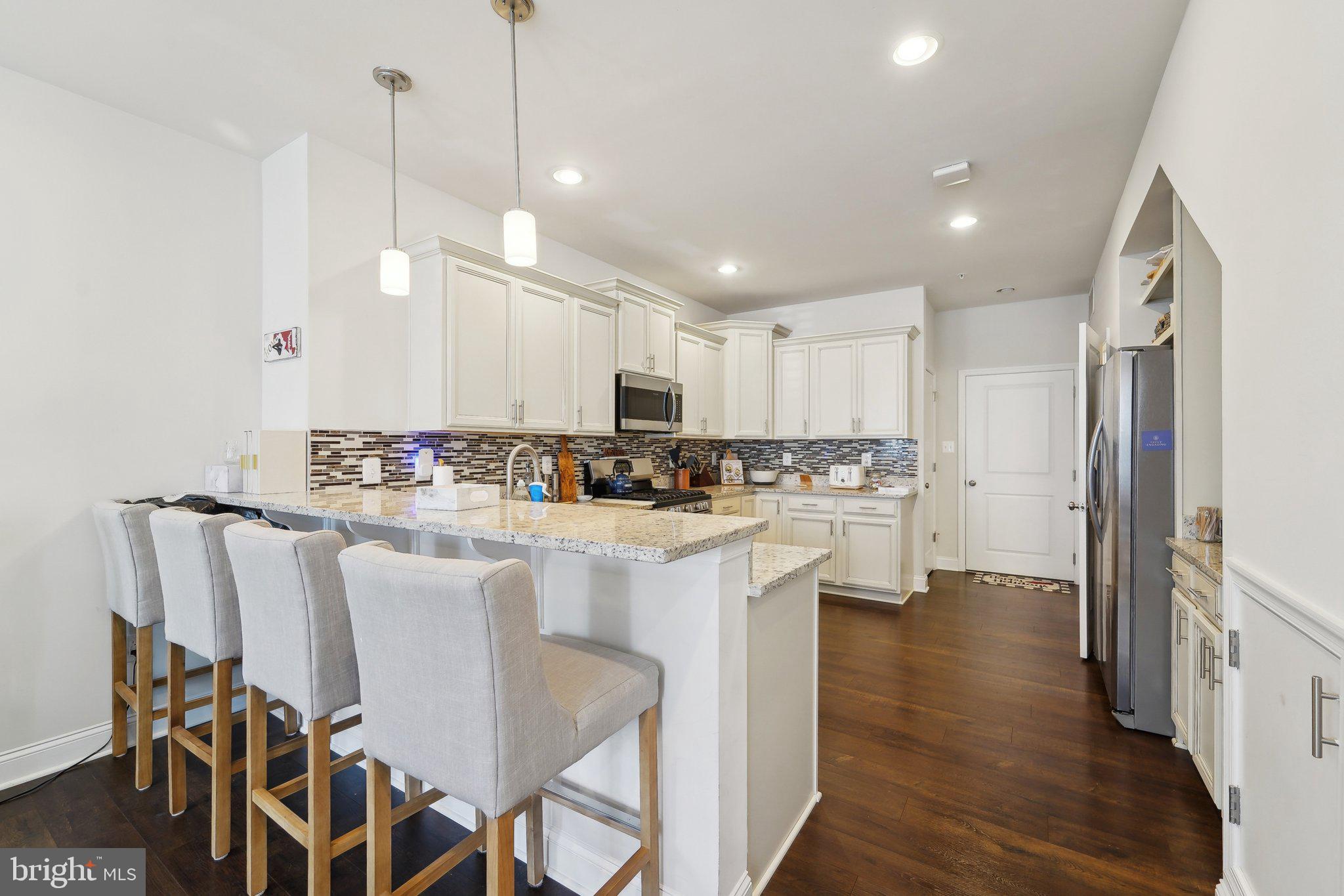 7101 Macon Street Frederick, MD 21703 - Photo 10 of 38 a kitchen with stainless steel appliances granite countertop a refrigerator a sink dishwasher a stove and white cabinets with wooden floor