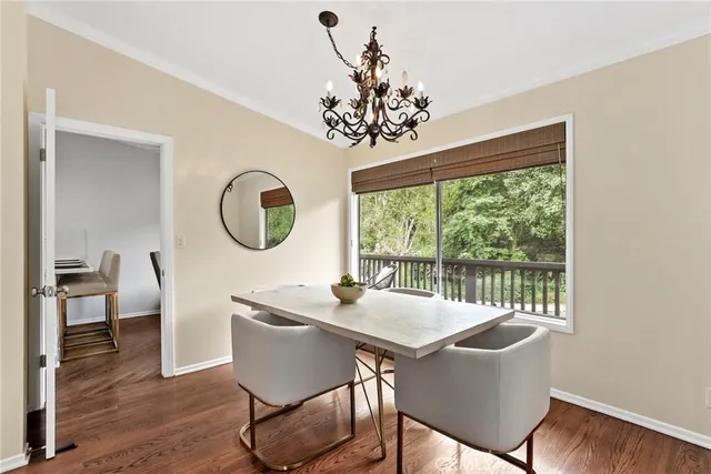 a dining room with wooden floor a chandelier a wooden table and chairs